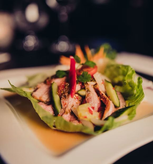 A Thai spicy salad plated with fresh herbs and chilli